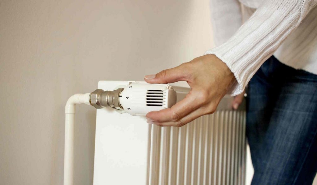 nő felcsavarja a fűtést a radiátoron