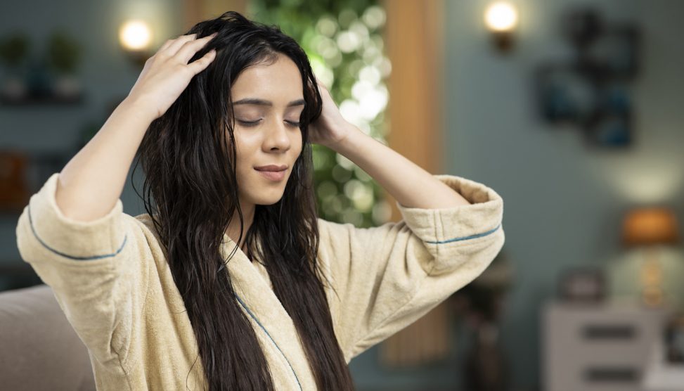 meleg olajos hajpakolást ken a hajára egy szép fiatal nő