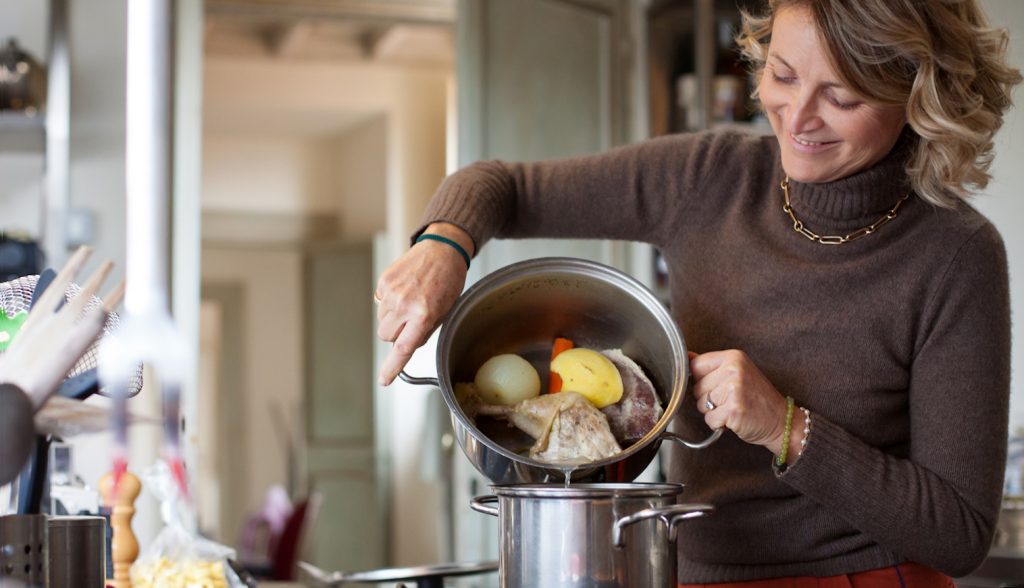 habos húslevest szűr át egy háziasszony a konyhában
