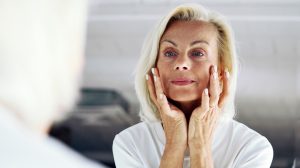 szép idős nő nézi magát a tükörben