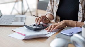 Nő számológéppel számol az asztalnál