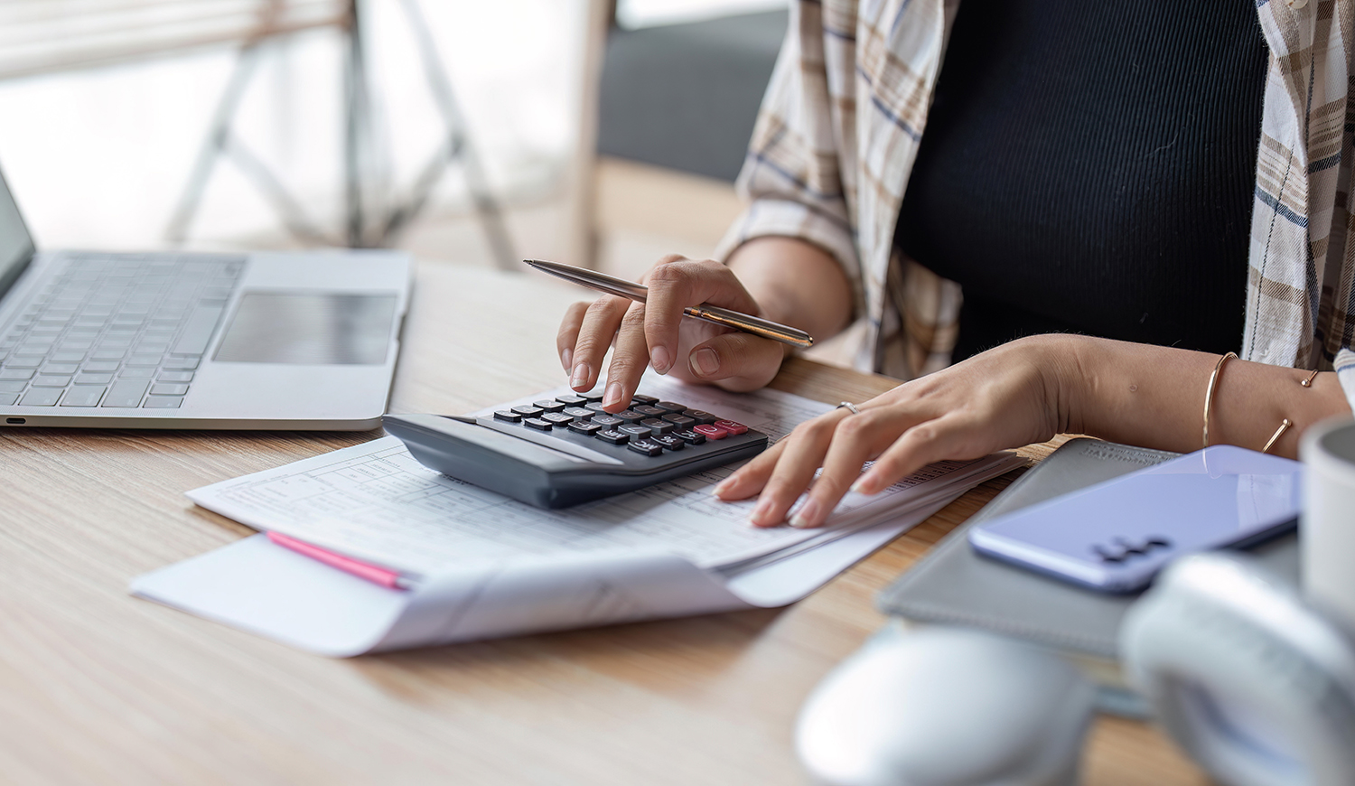 Nő számológéppel számol az asztalnál