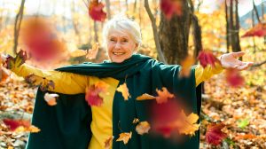 Boldog idős nő az erdőben színes falevelekkel