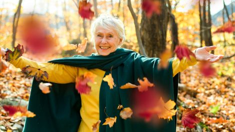Boldog idős nő az erdőben színes falevelekkel