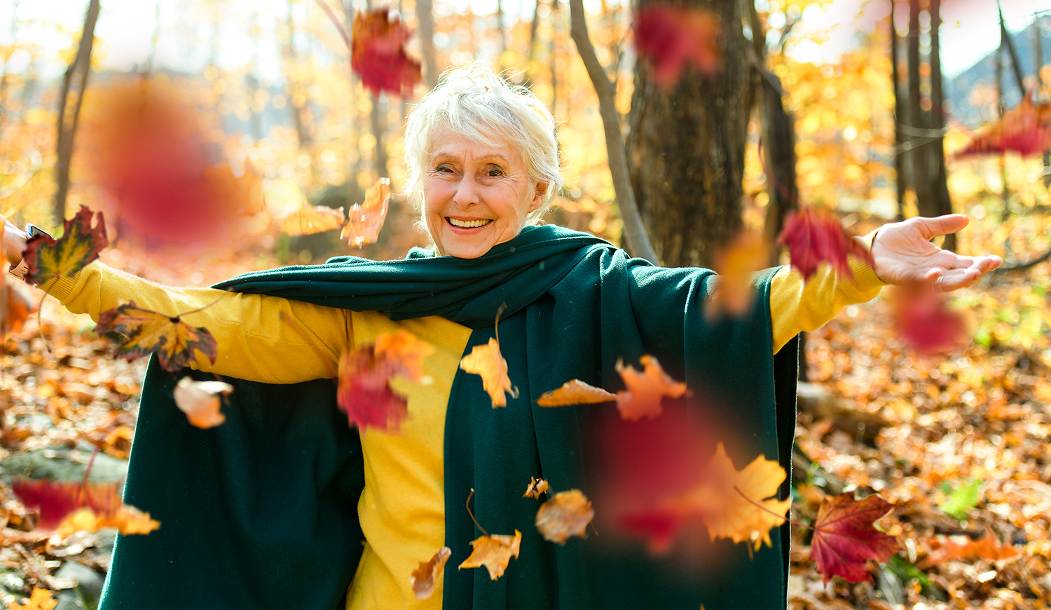 Boldog idős nő az erdőben színes falevelekkel