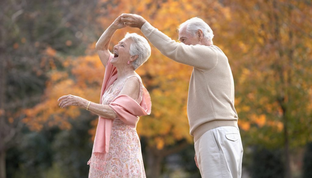 boldog idős pár táncol az őszi erdőben mert fitt az immunrendszerük