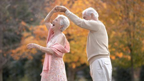 boldog idős pár táncol az őszi erdőben mert fitt az immunrendszerük