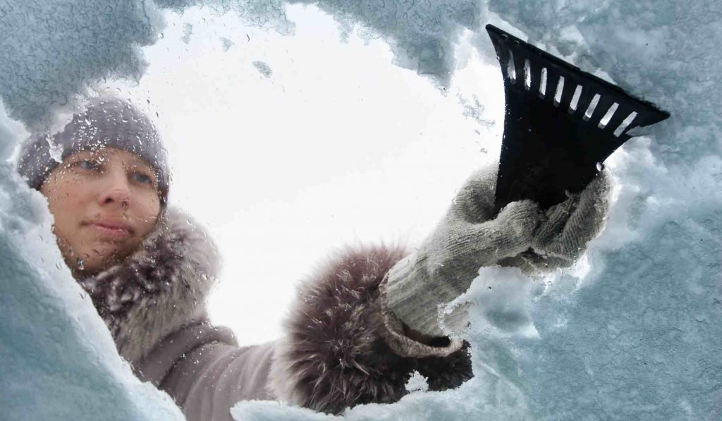 Nő kapargatja a jeges szélvédőt