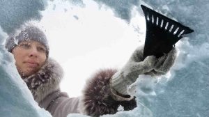 Nő kapargatja a jeges szélvédőt