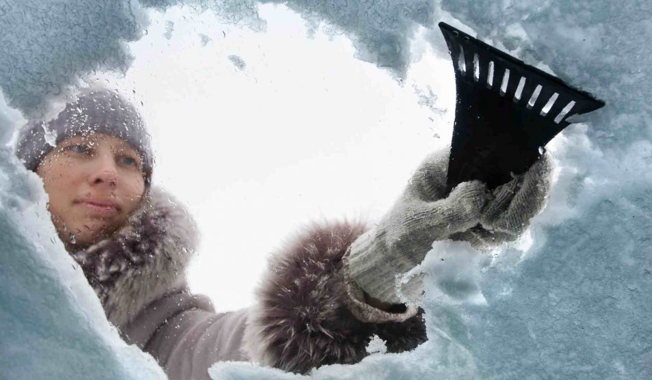 Nő kapargatja a jeges szélvédőt