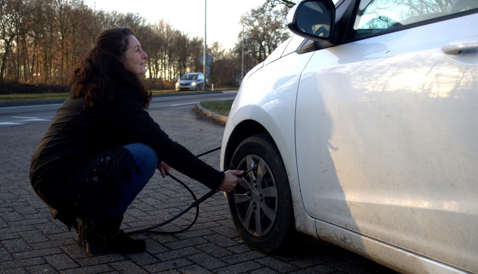 keréknyomást ellenőriz ősszel és télen egy nő az autóján