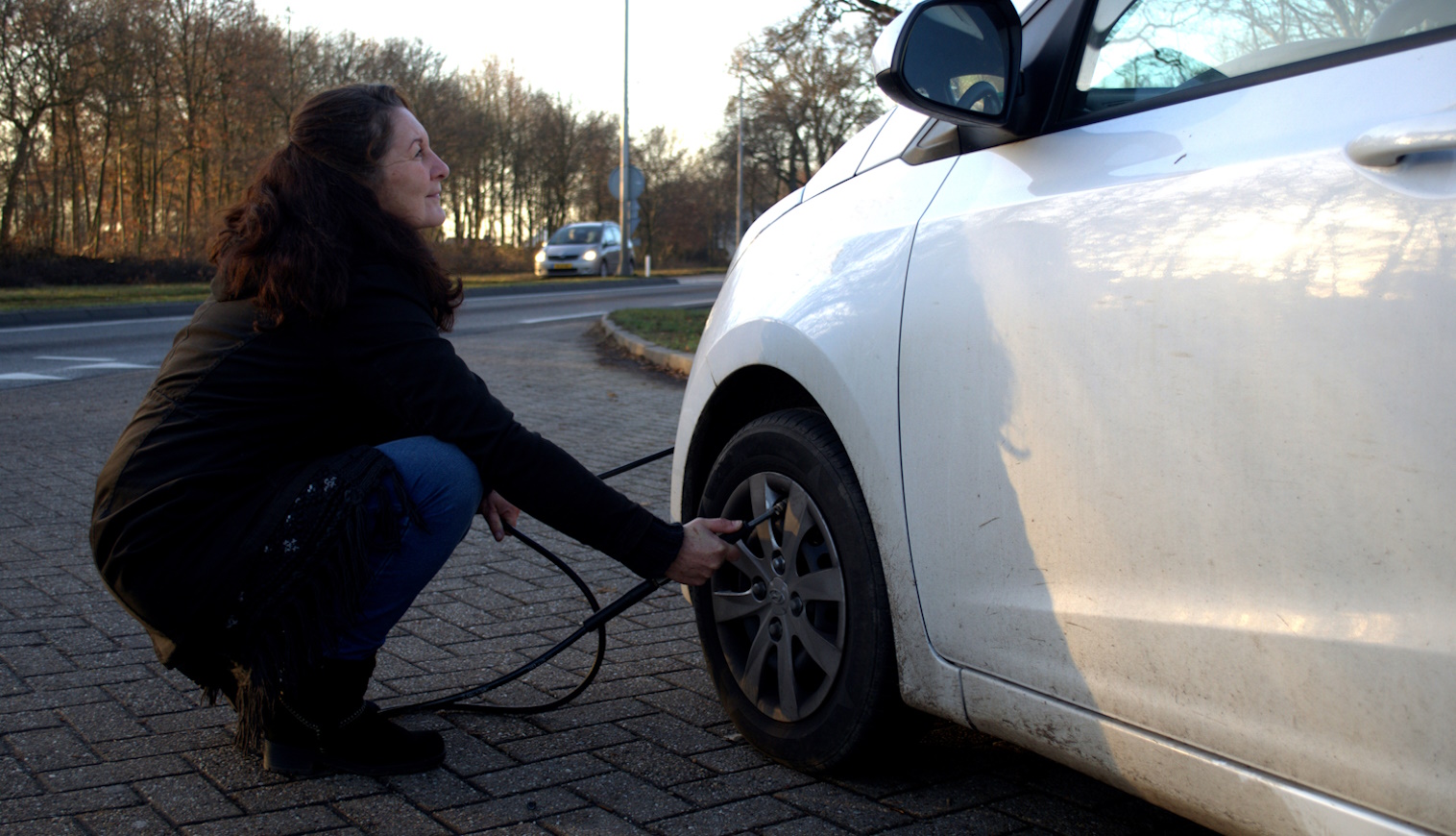 keréknyomást ellenőriz ősszel és télen egy nő az autóján
