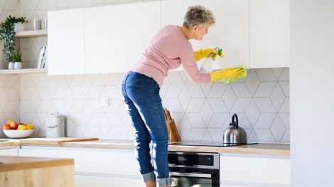 konyhaszekrényt takarít zsírtól egy idős nő