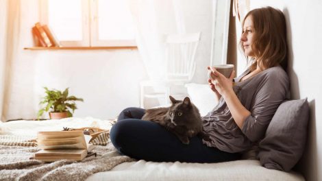 nő a cicájával a hálószobában