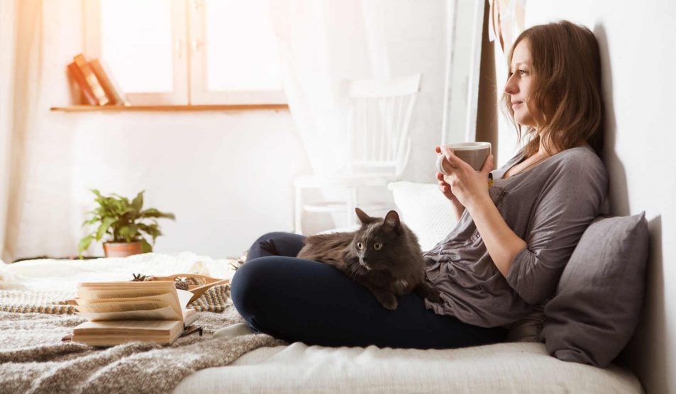 nő a cicájával a hálószobában