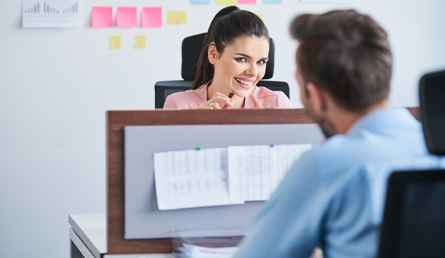 Fiatal nő flörtöl a munkahelyén az íróasztala felett munkatársával