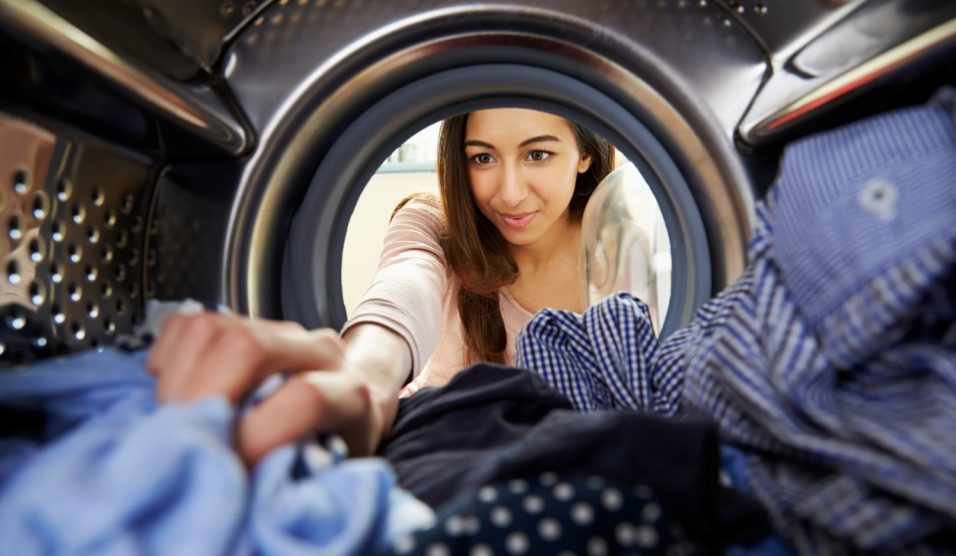 fiatal nő mosógépbe pakol