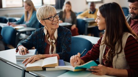 Idősebb nő beszélget fiatalabb osztálytársával az osztályteremben tartott oktatási kurzus során.