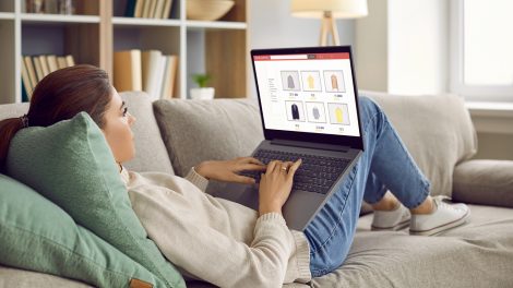 Nő a kanapén fekszik ölében laptoppal, és online vásárol