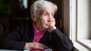 Egy idős nő néz ki az ablakon