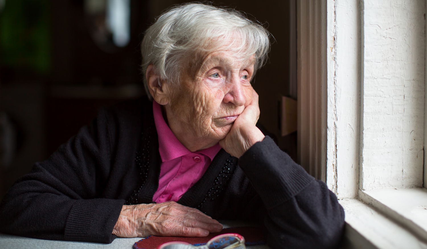 Egy idős nő néz ki az ablakon