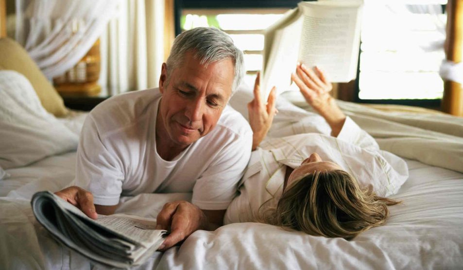 középkorú pár az ágyban olvas
