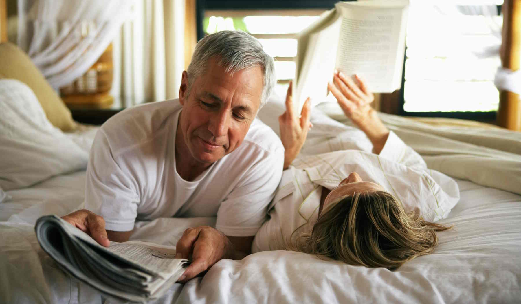középkorú pár az ágyban olvas