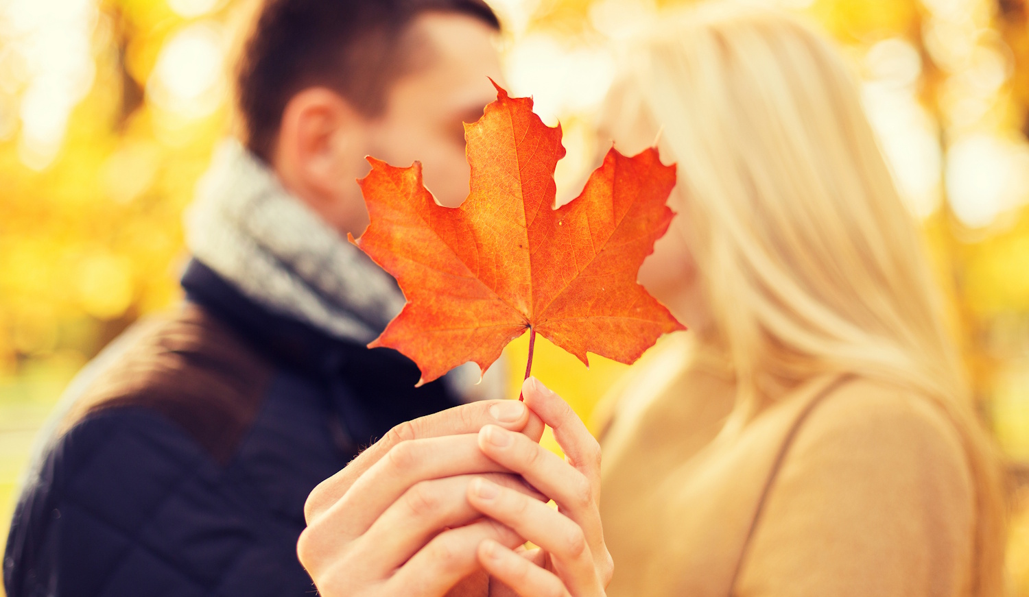 Egy nő és egy férfi csókolózik egy falevelet maguk elé tartva