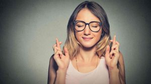 szemüveges lány keresztezi az ujjait, hogy szerencséje legyen