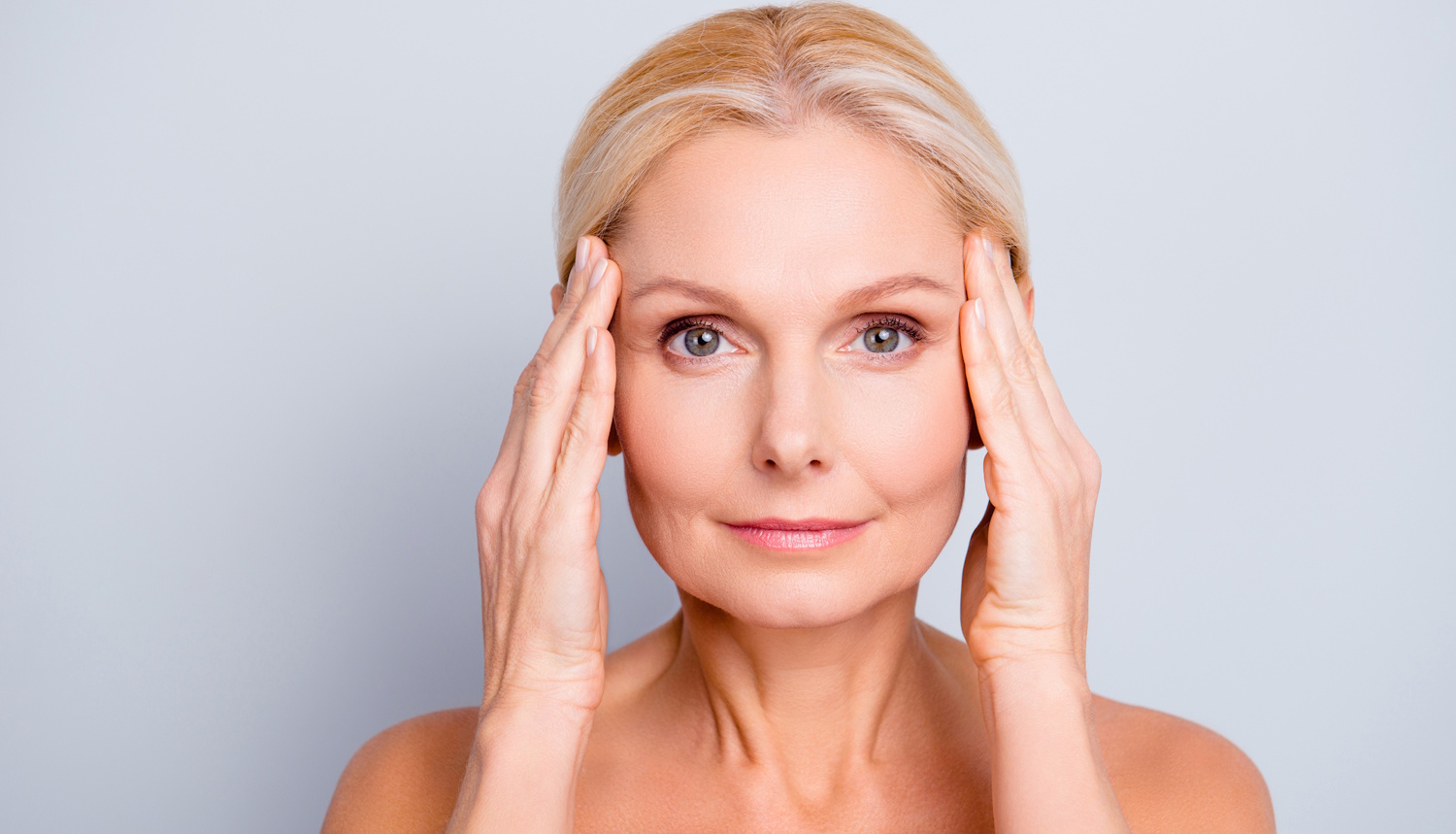 arcát fogó mosolygó nő