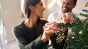 Boldog fiatal pár karácsonyfát díszít