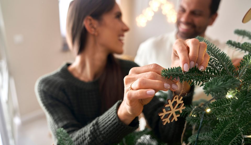 Boldog fiatal pár karácsonyfát díszít
