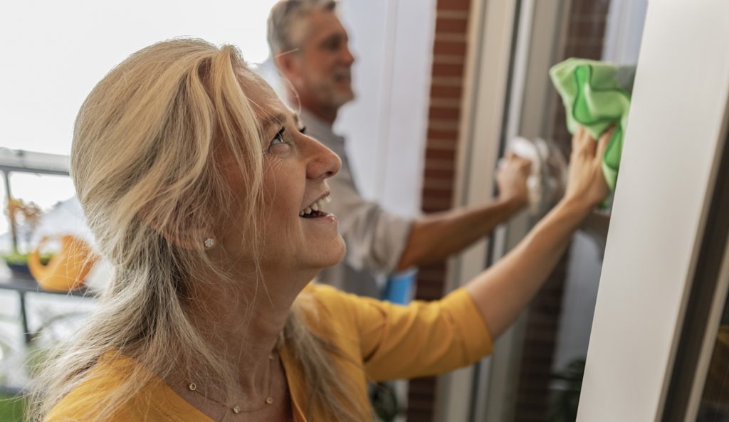boldog középkorú nő ablakot mos a férjével glicerinnel