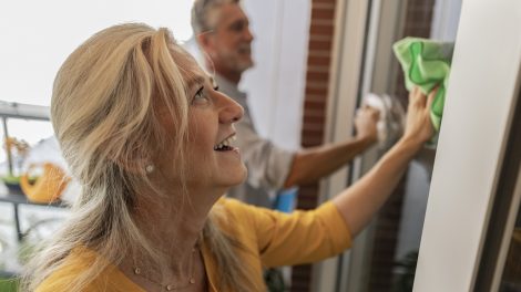 boldog középkorú nő ablakot mos a férjével glicerinnel