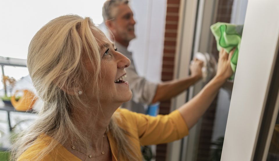 boldog középkorú nő ablakot mos a férjével glicerinnel