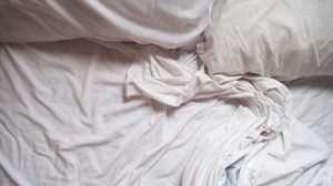 fehér ágy fehér ágyneművel gyűrötten