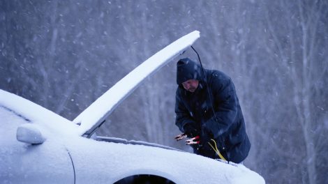 férfi télen autót bikáz, mert nem indul a kosi