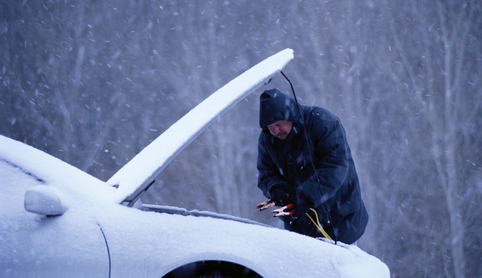 férfi télen autót bikáz, mert nem indul a kosi