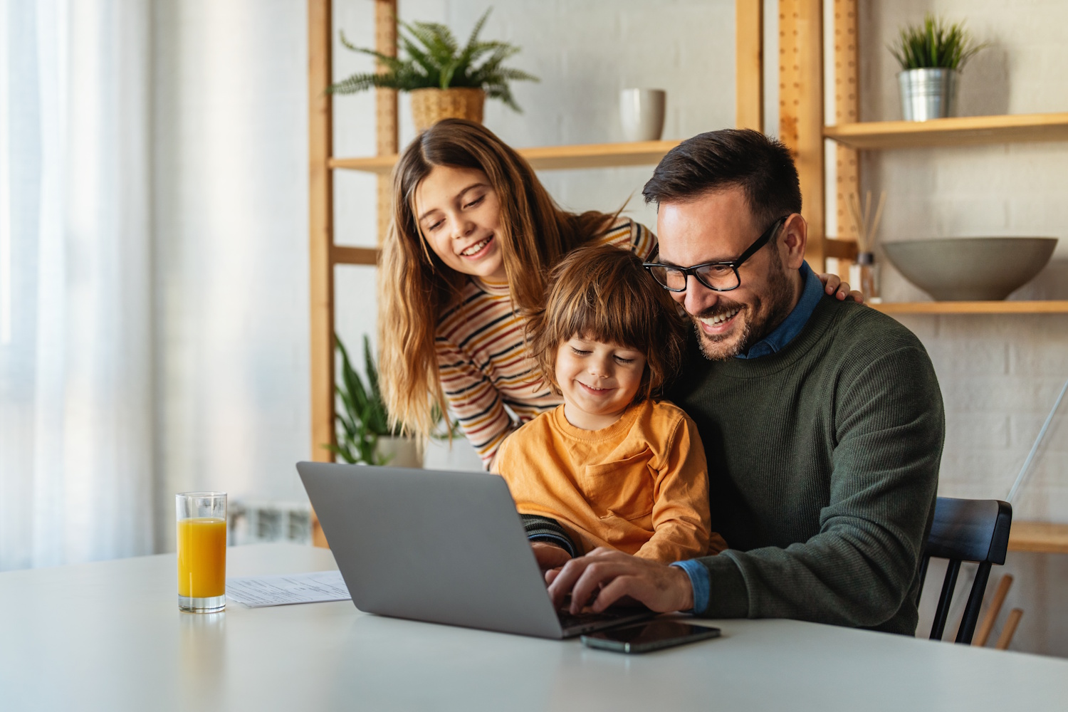 Egy apa a lánya és a fia ülnek a laptop előtt