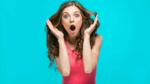 Nő látványosan meglepődik a kék háttér előtt