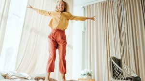 Idősebb nő ugrál az ágyon