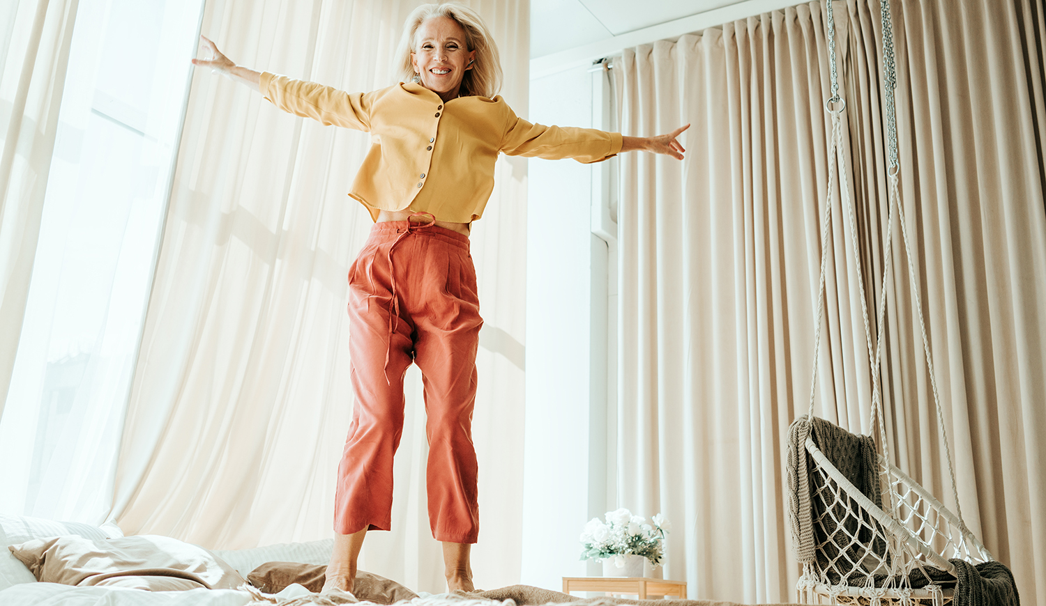 Idősebb nő ugrál az ágyon