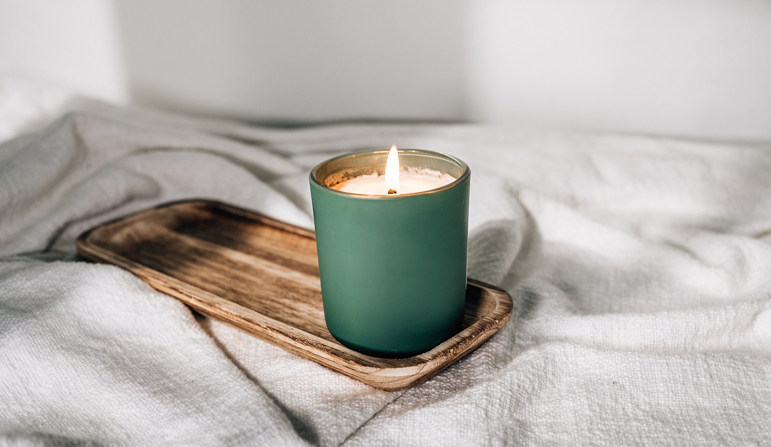 Zöld gyertya az ágyon egy fa tálcán