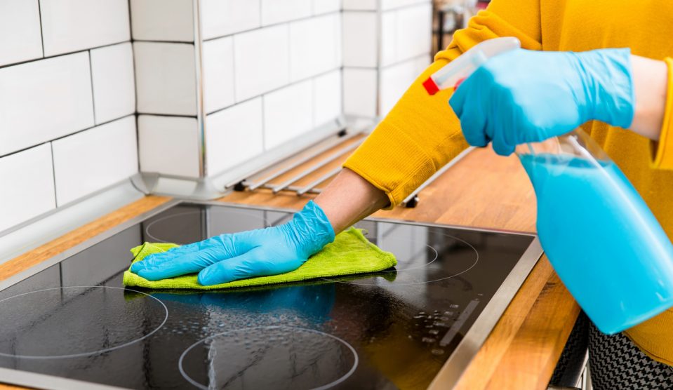 nő az elektromos főzőlapot takarítja