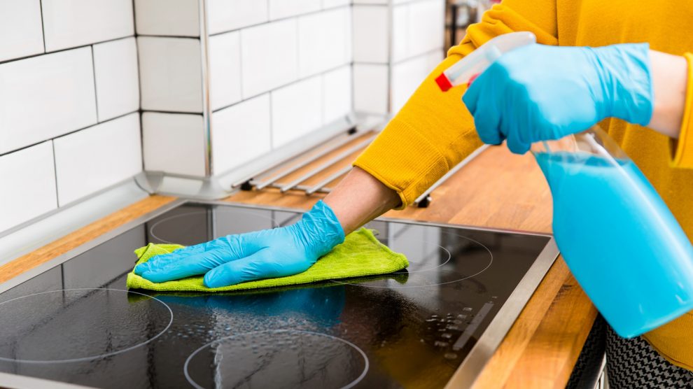 nő az elektromos főzőlapot takarítja