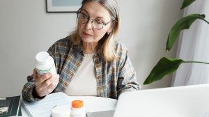 Középkorú nő olvassa a gyógyszerleírást a dobozon