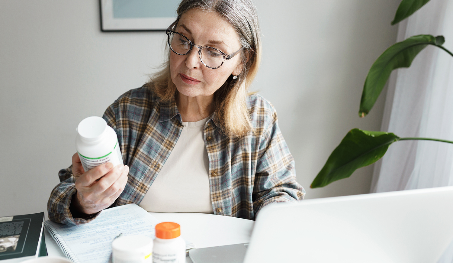 Középkorú nő olvassa a gyógyszerleírást a dobozon