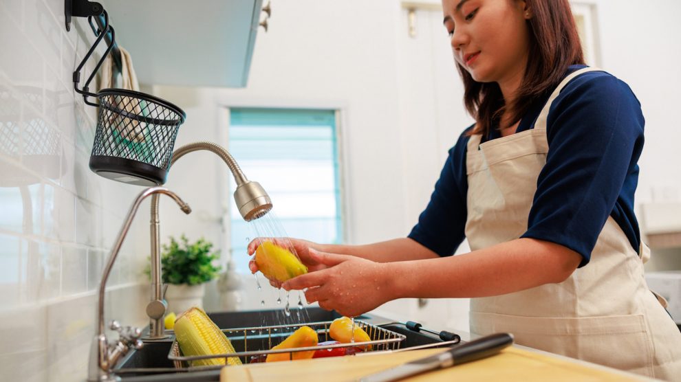 zöldséget és gyümölcsöt mos egy nő a csap alatt