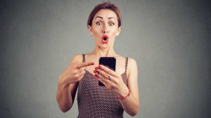 nő telefonját mutat valamit és látványosan meglepődik