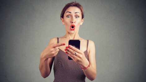 nő telefonját mutat valamit és látványosan meglepődik